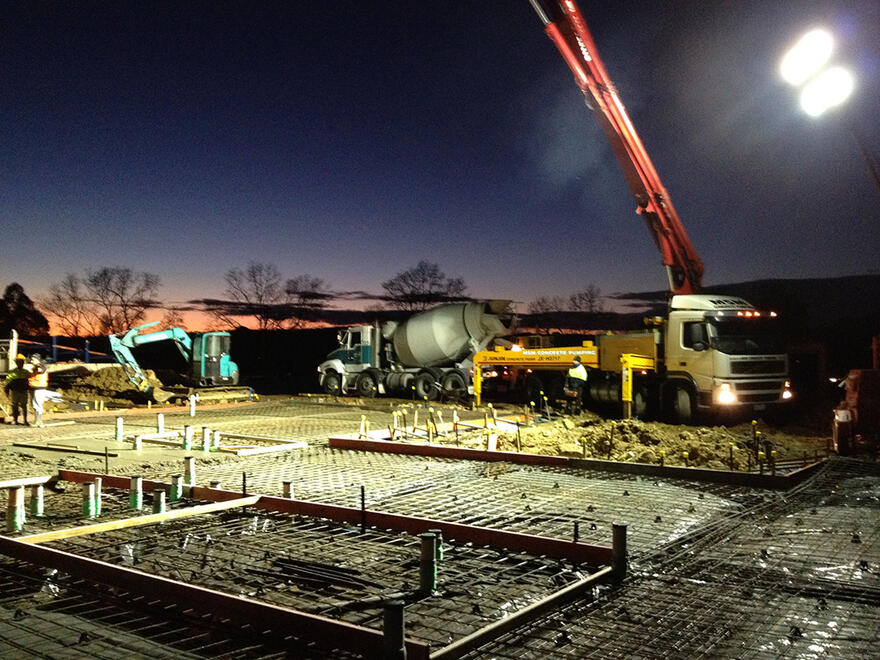 Concrete truck and pump pouring slab foundations at night in Melbourne